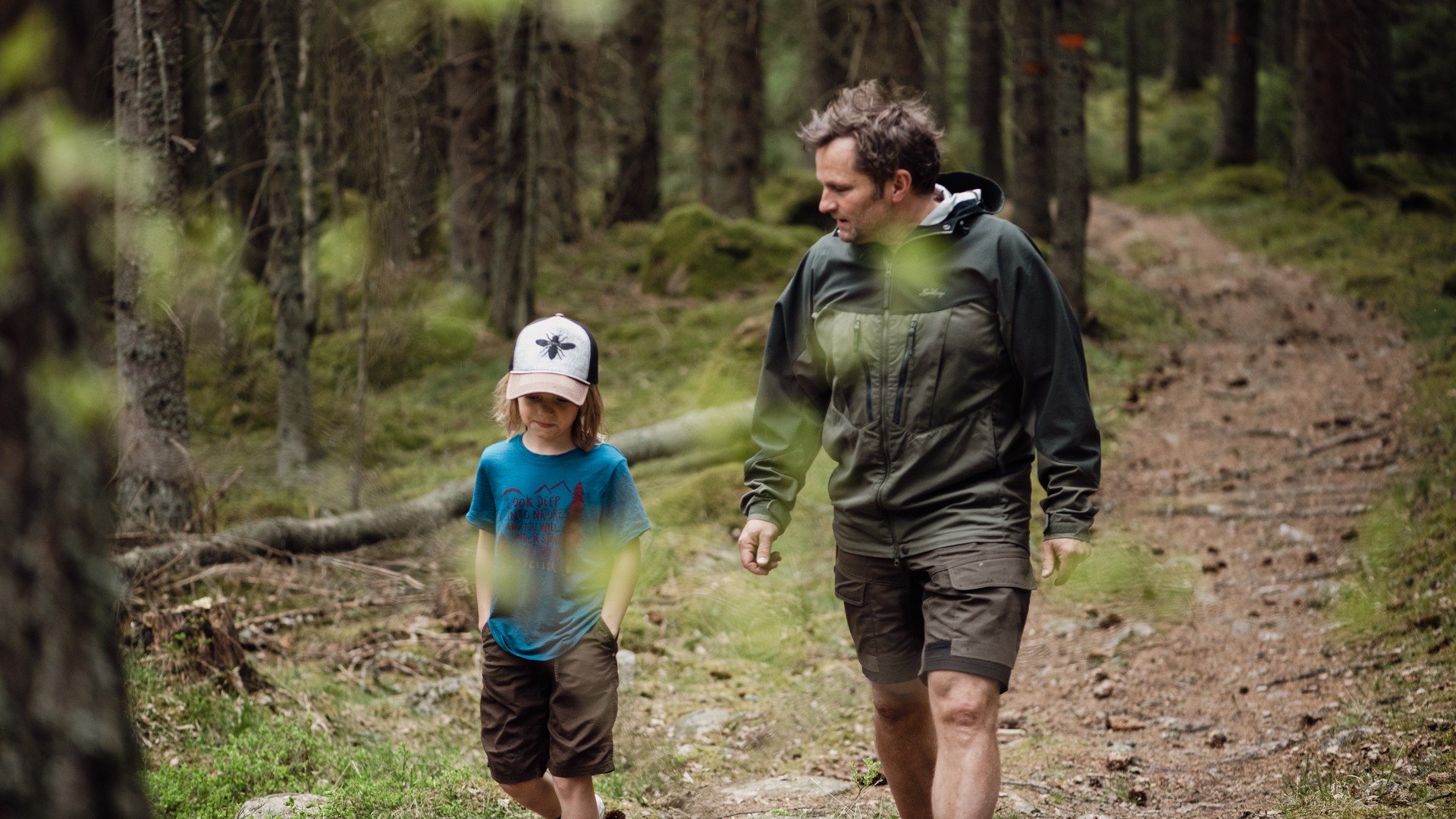 Ett barn och en vuxen på promenad i skogen.