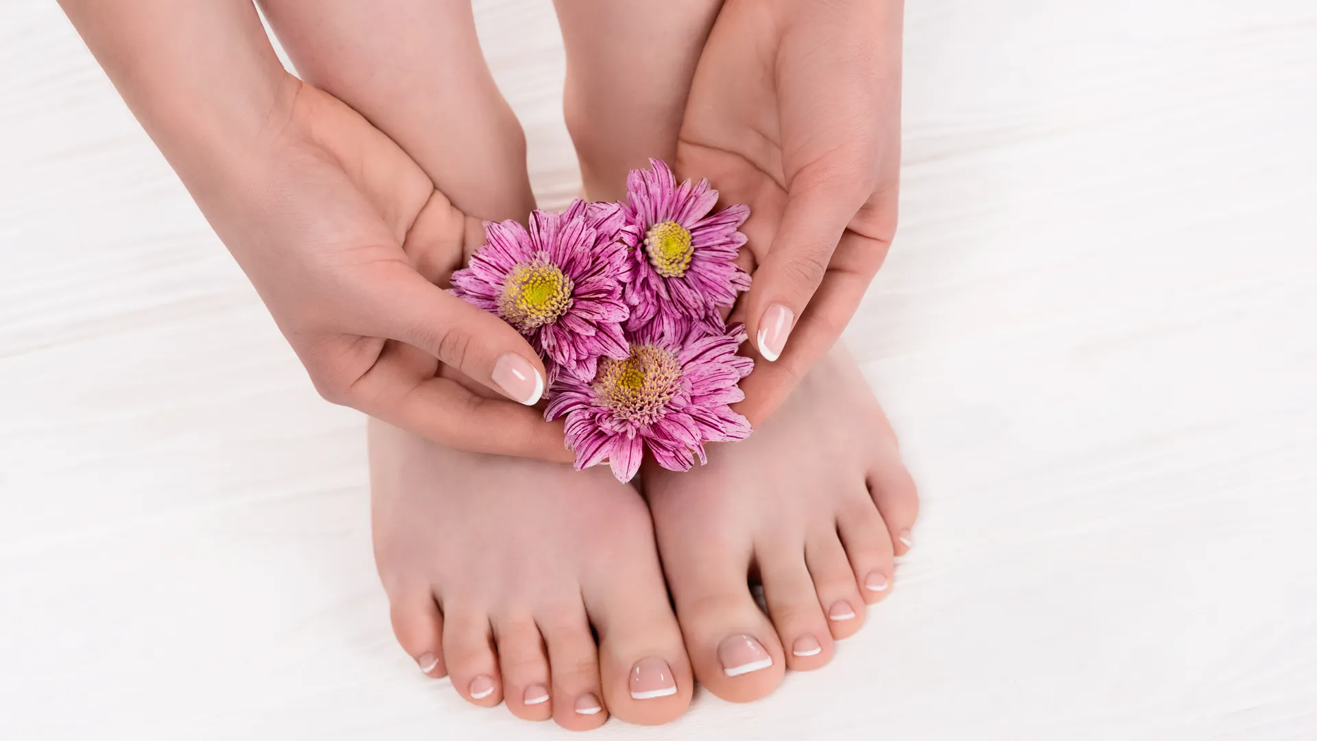 Bild på fötter där en person håller rosa blommor över fötterna