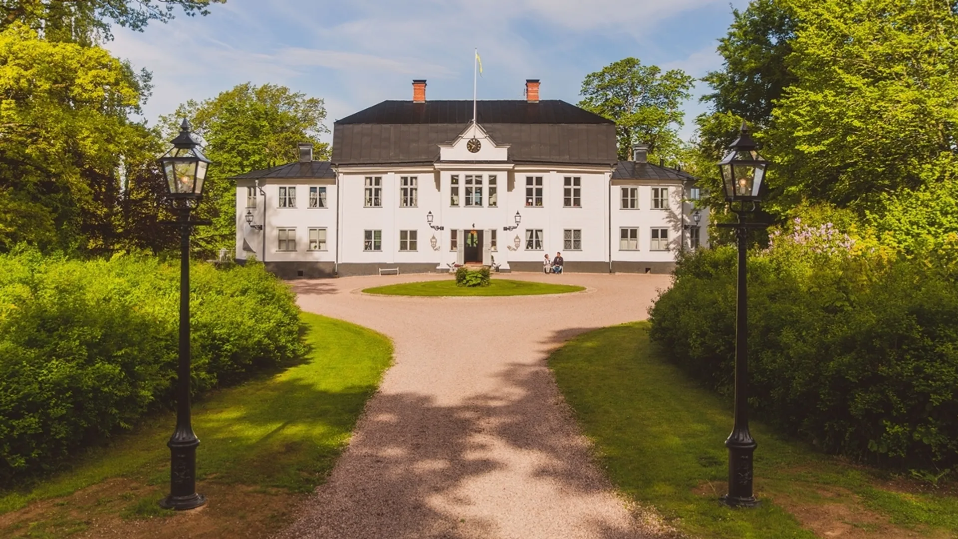 Ett stort vitt hus omgivet av lummiga gröna träd.