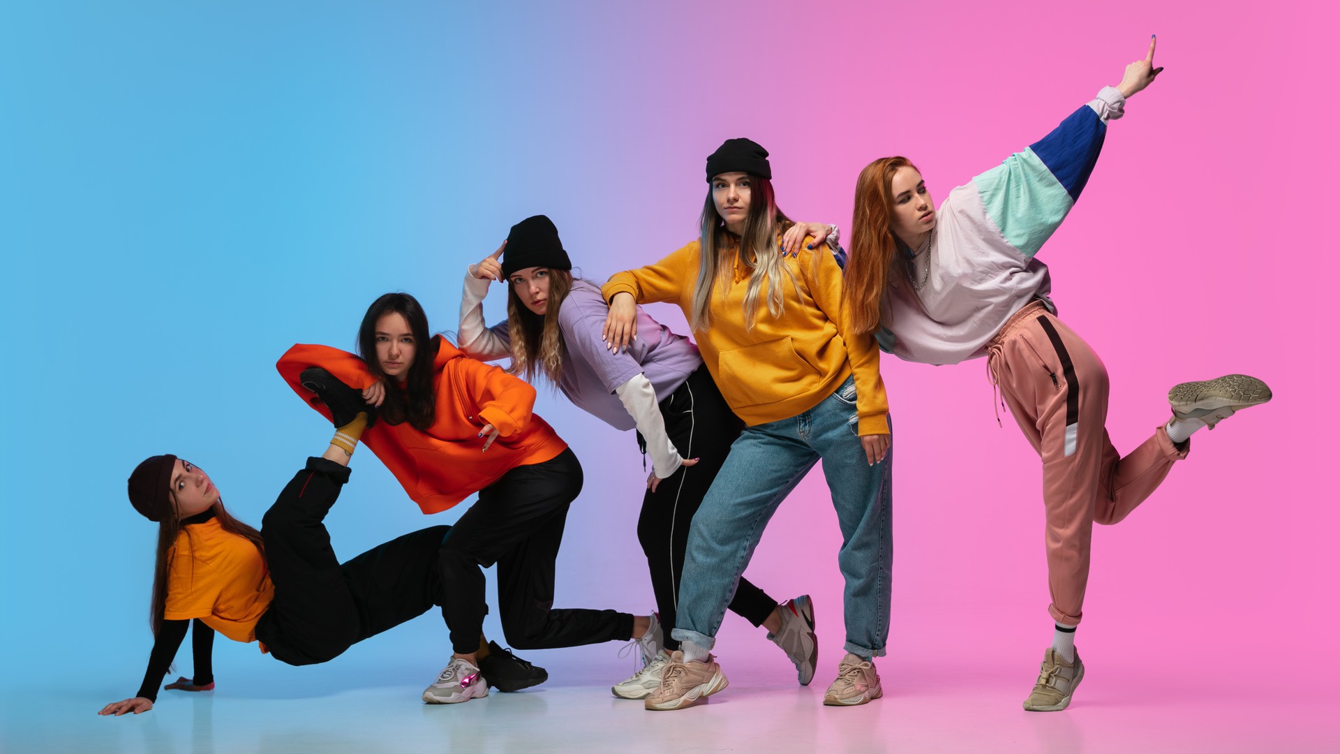 Group of dancers, boys and girls dancing hip-hop in stylish clothes on colorful gradient background at dance hall in neon. 