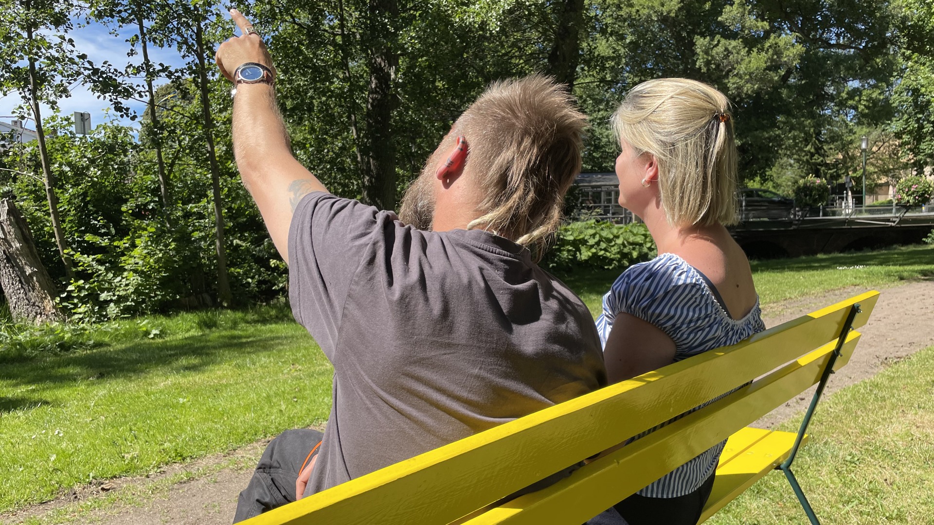 Två personer sitter på en gul bänk och pratar.