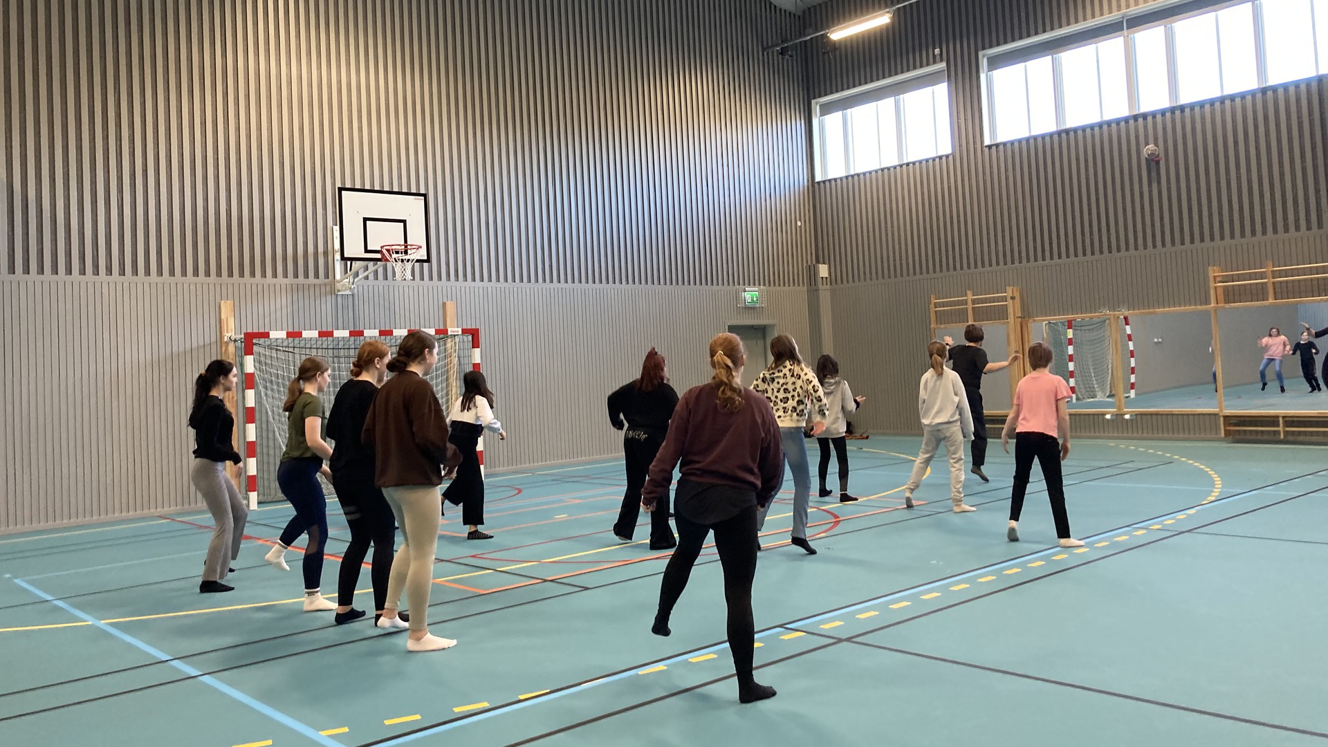 Personer dansar i en gymnastiksal.