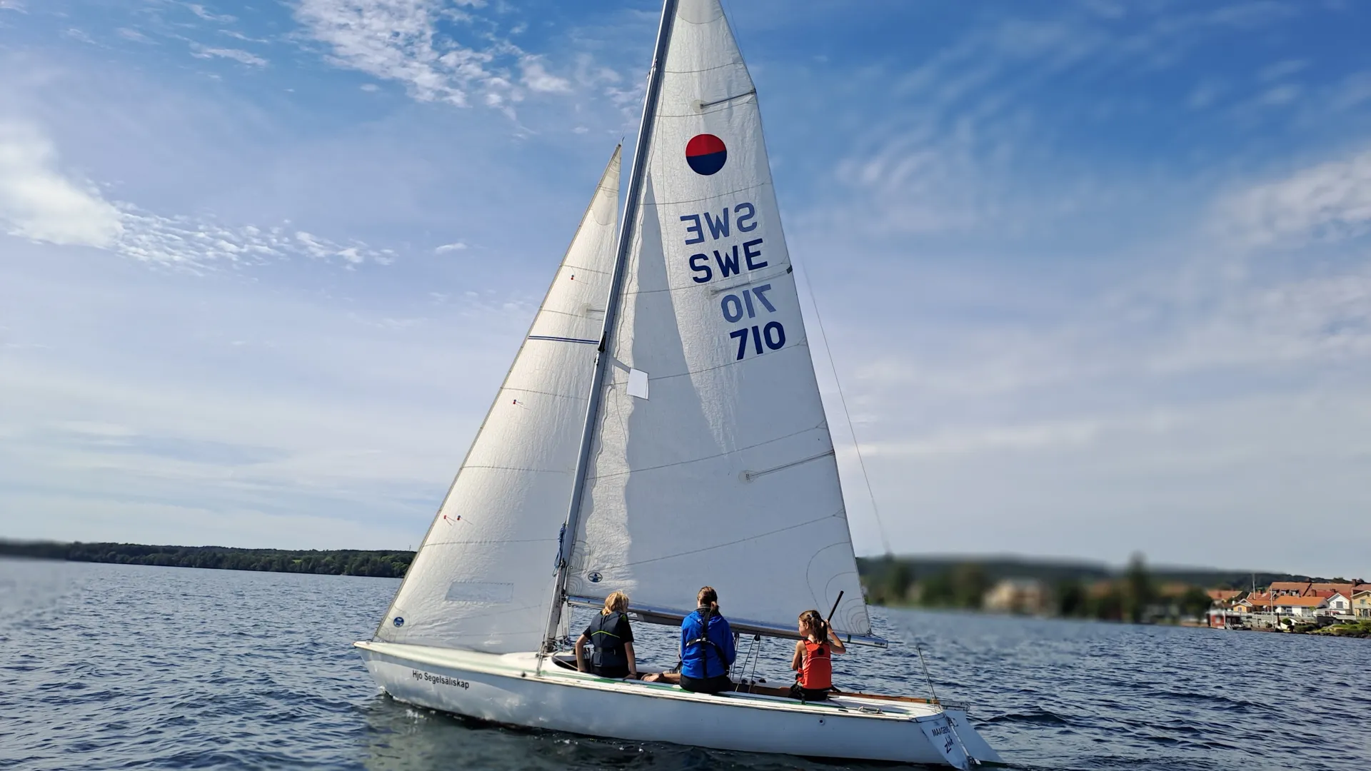 Segelbåt med tre personer i utanför Hjo hamn.