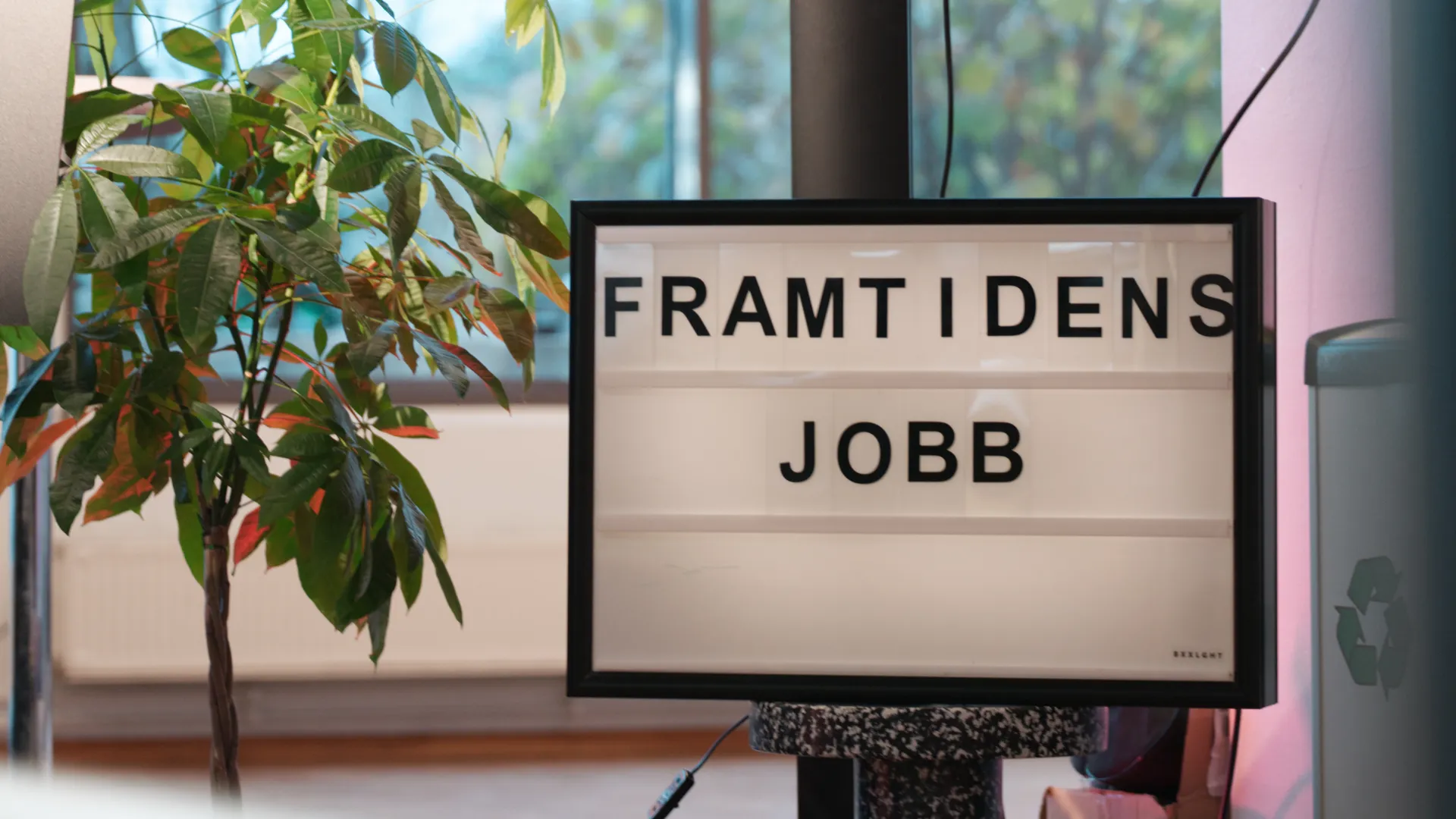 En skylt som sitter på en stolpe framför ett fönster