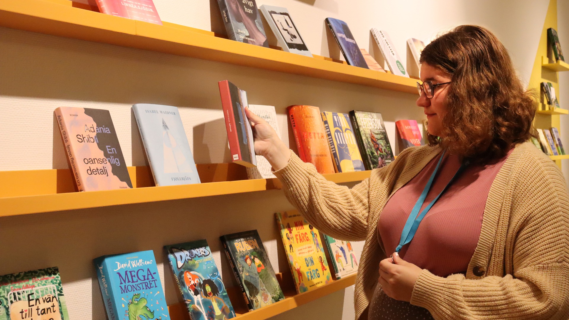 Feriepraktikanten Vera står vid en bokhylla på biblioteket.