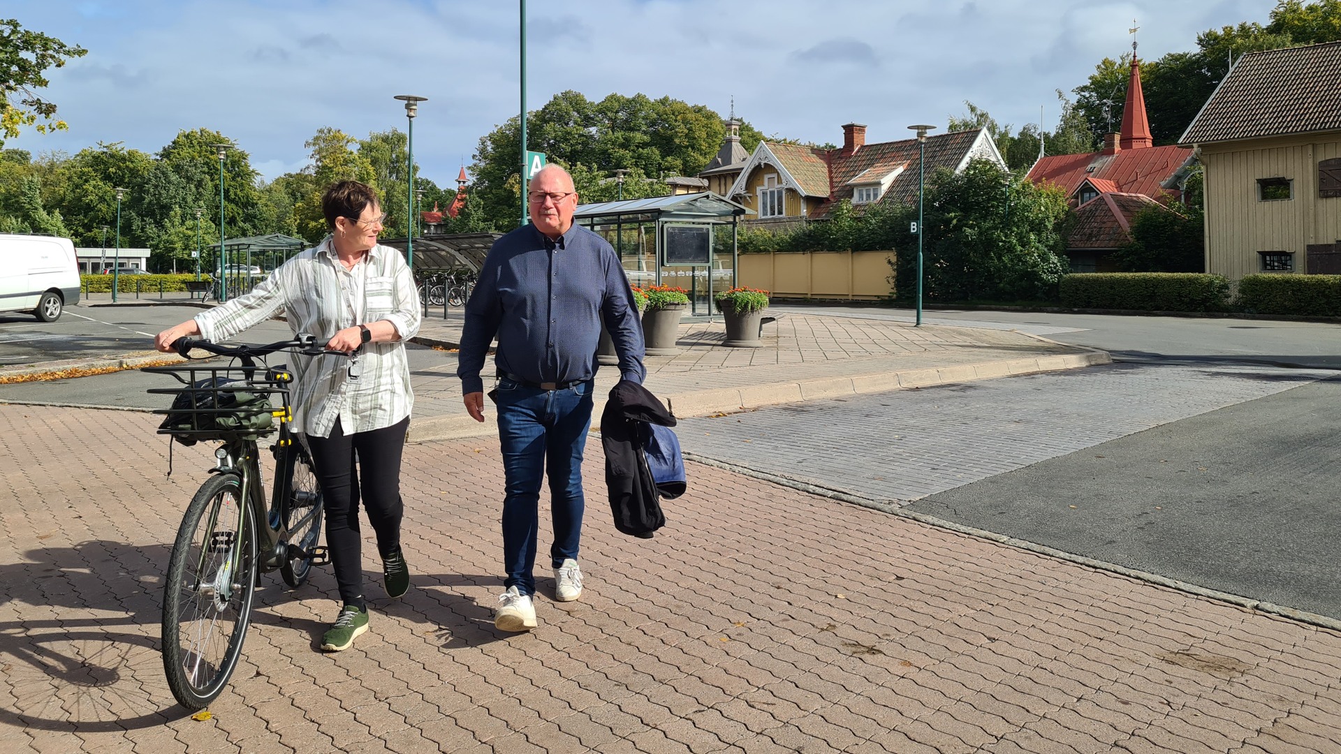 Kommundirektör Eva går med sin cykel vid busstationen, bredvid henne går fastighetschef Bo Adler.