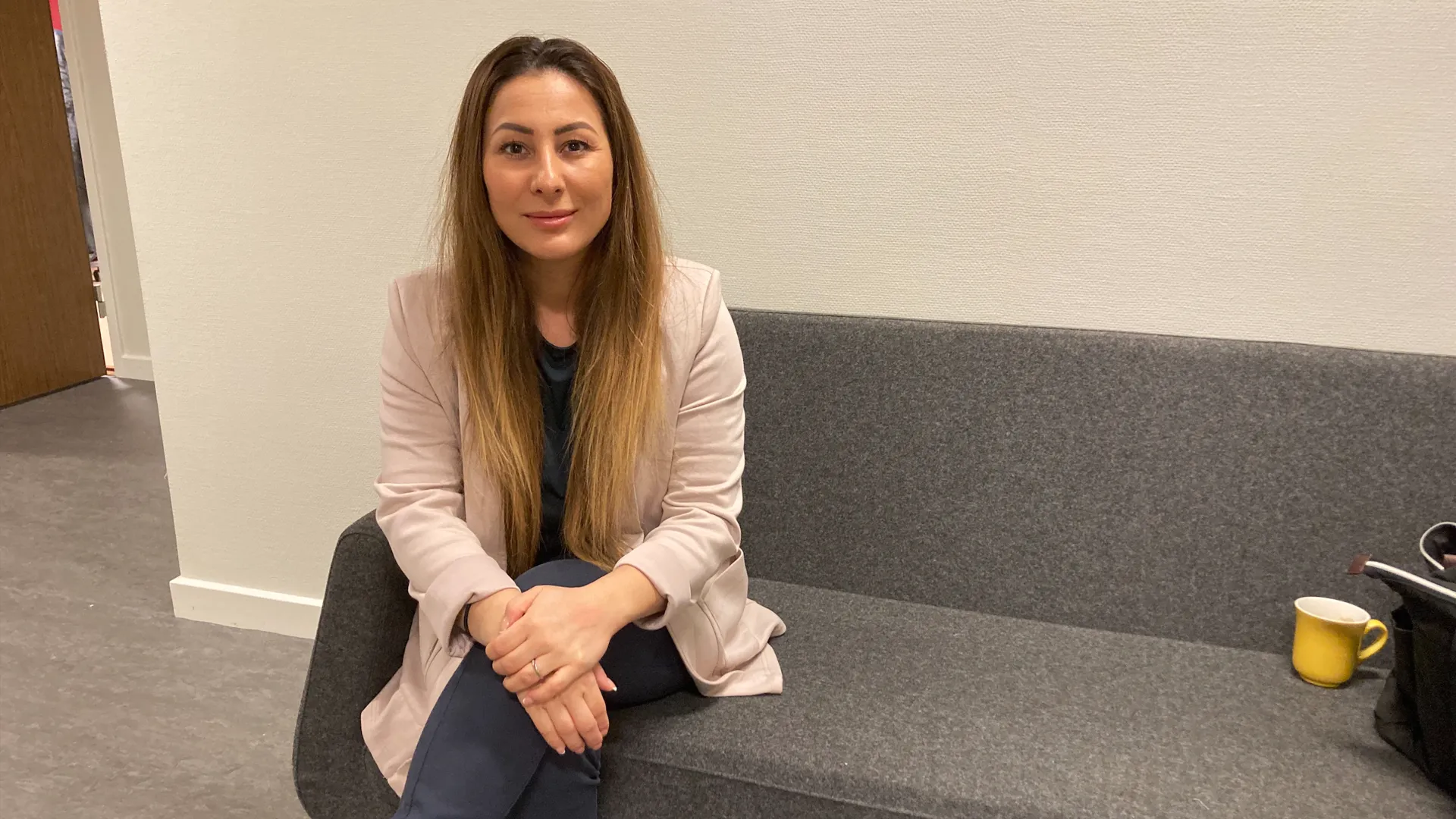 Daria Ramzi sitter på en soffa i en korridor.