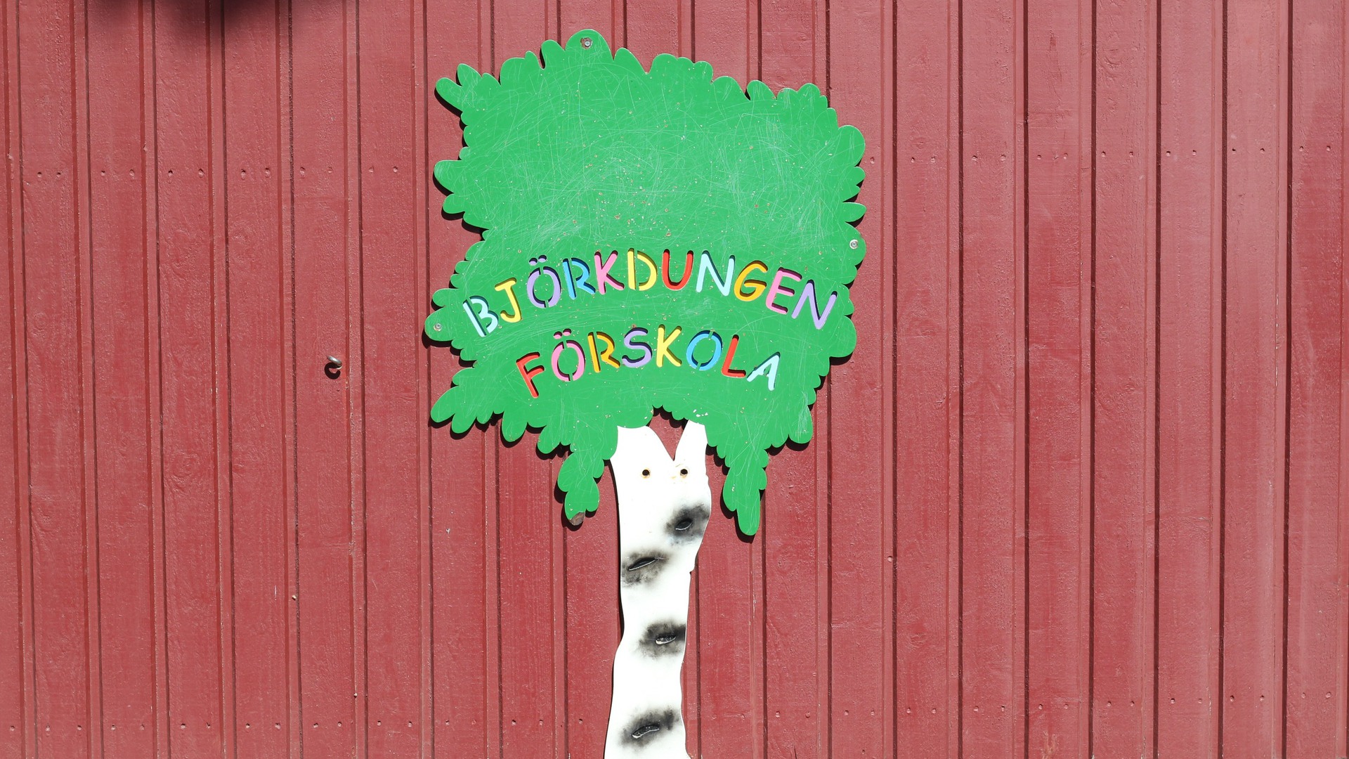 En skylt formad som en björk med texten "Björkdungens förskola" i olika färger i trädkronan.
