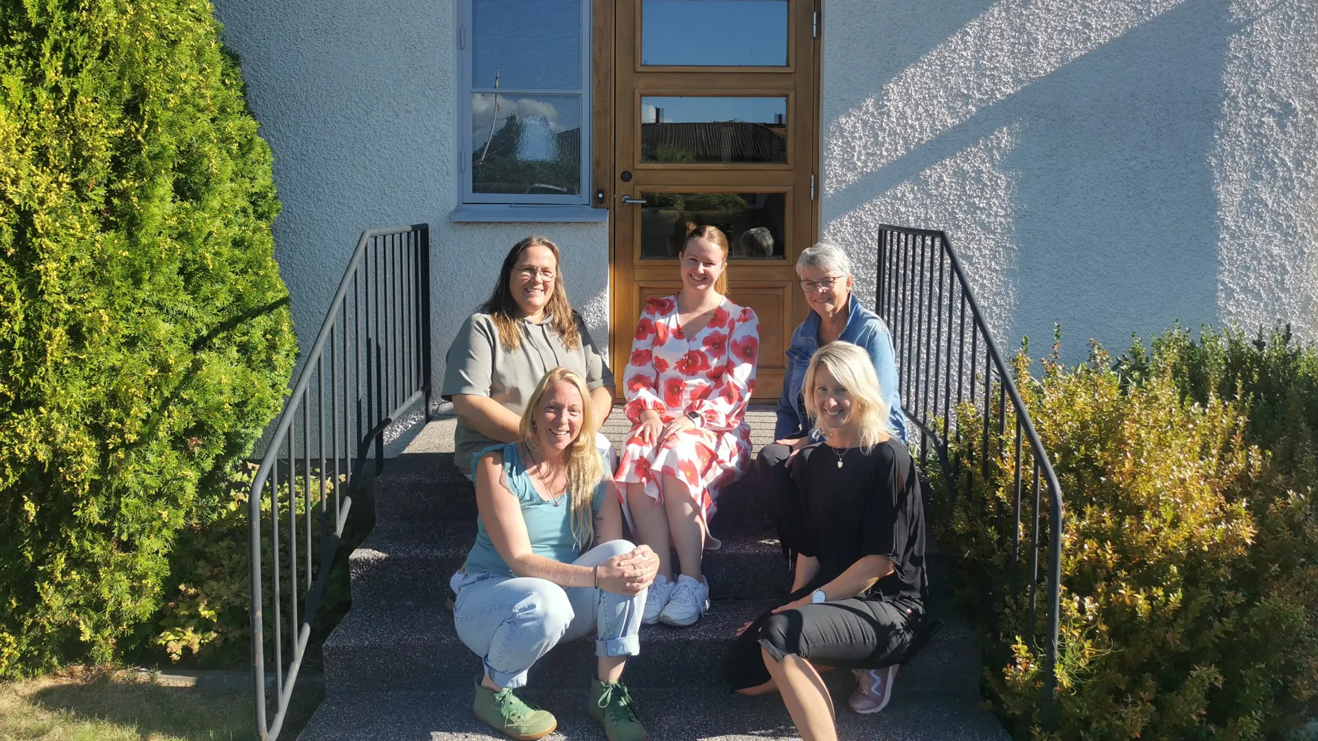 5 personer som sitter på en trappa.