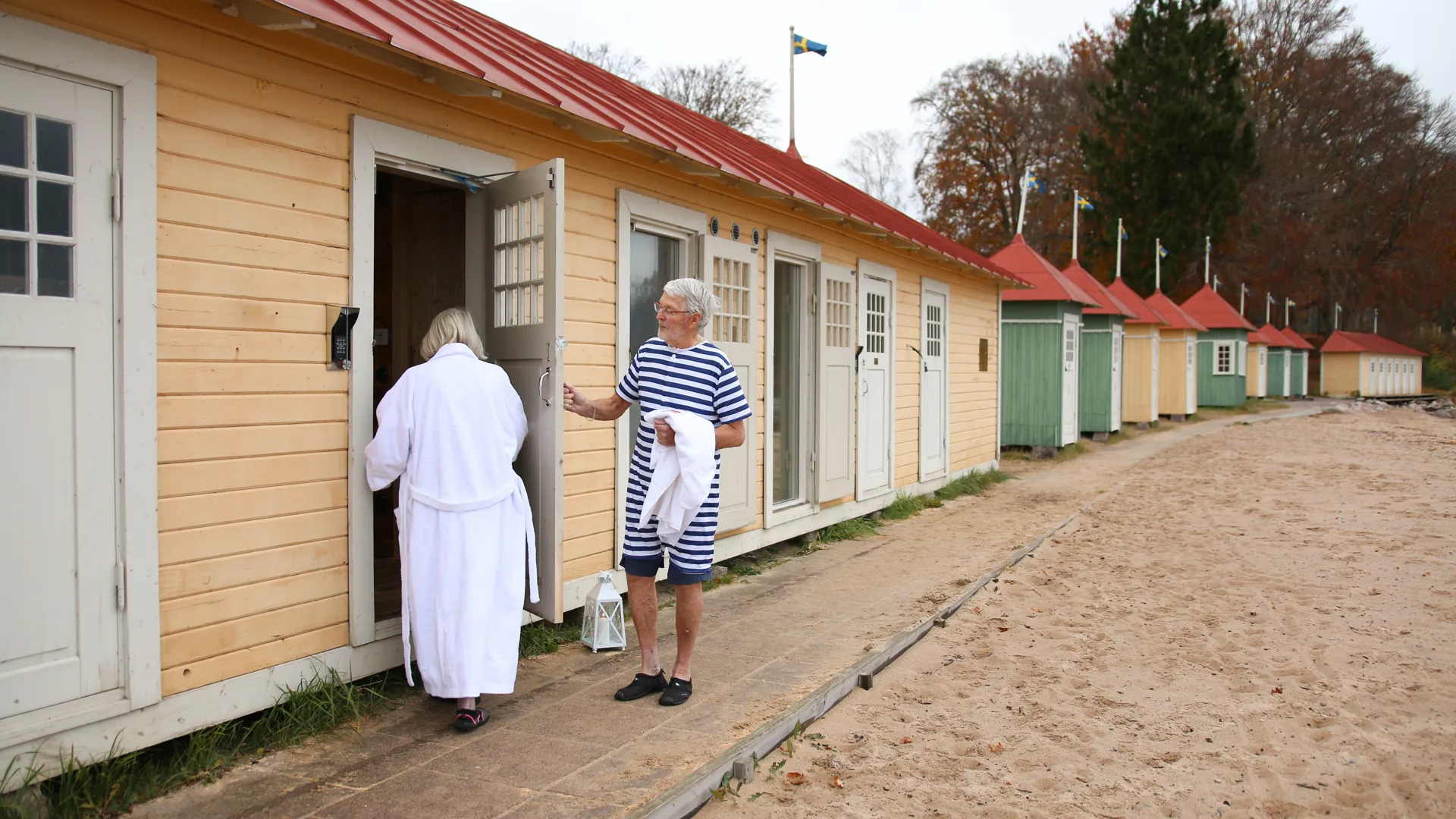 Ett par i badkläder och morgonrock utanför badhytterna på Guldkroksbadet.