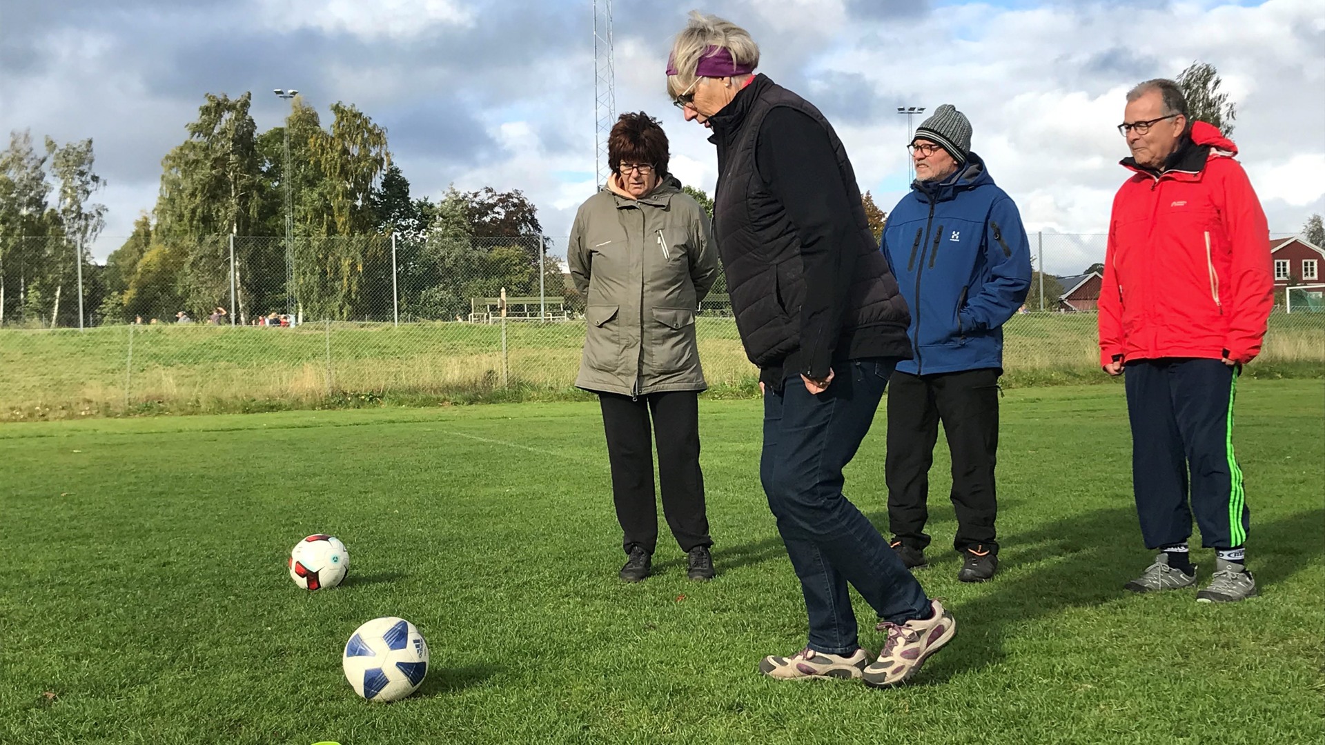 Fyra personer står på en fotbollsplan med två bollar
