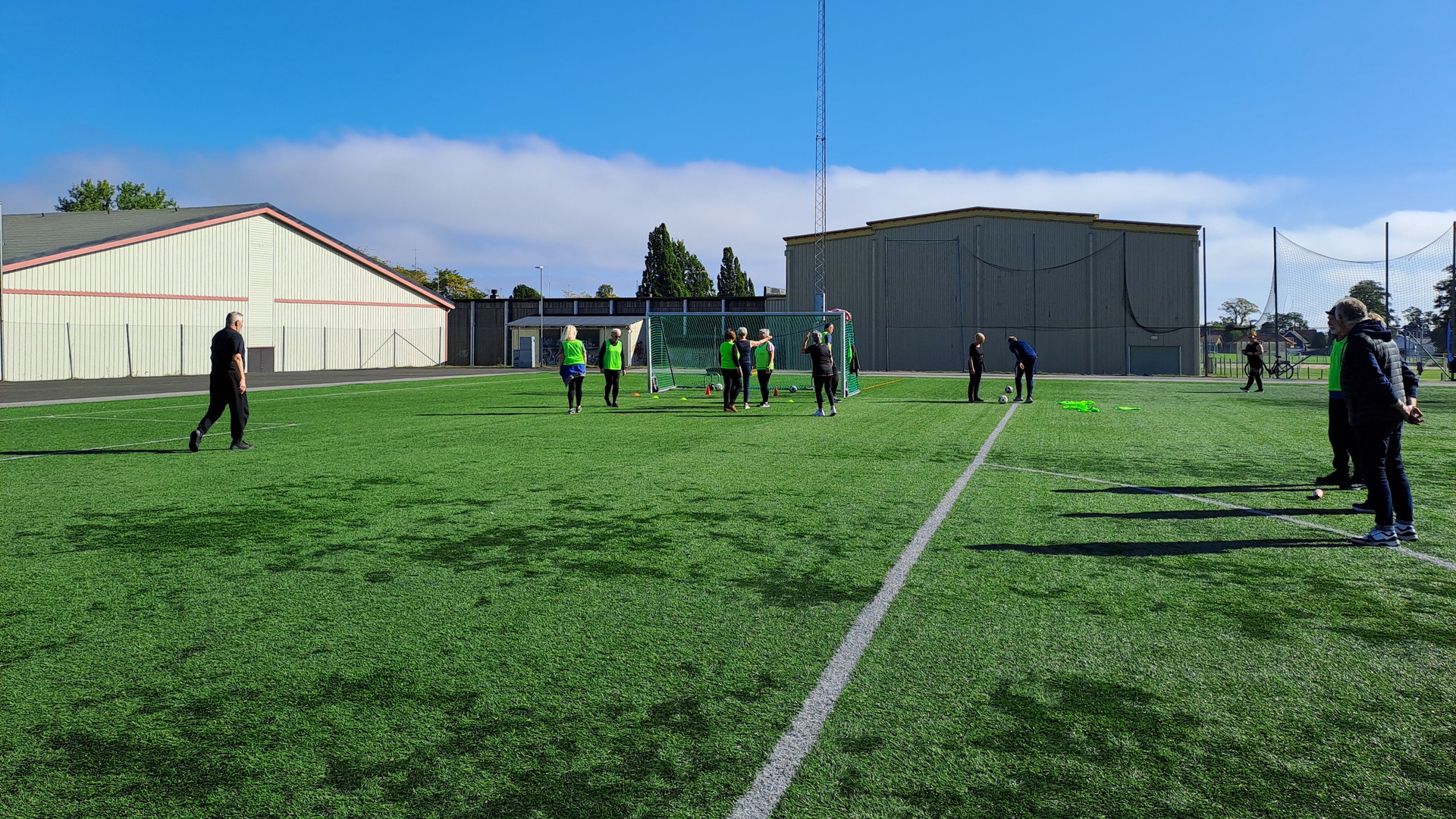 Några pensionärer spelar gåfotboll på konstgräsplanen under blå himmel