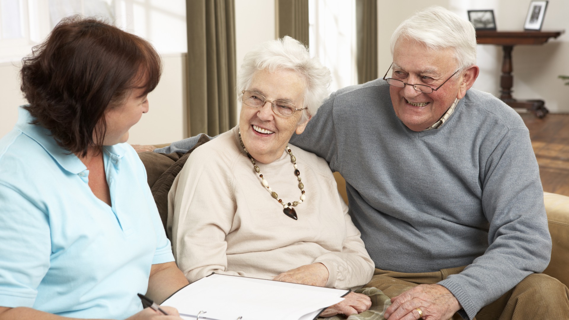 Äldre leende par i diskussion med Kvinna i hemmiljö