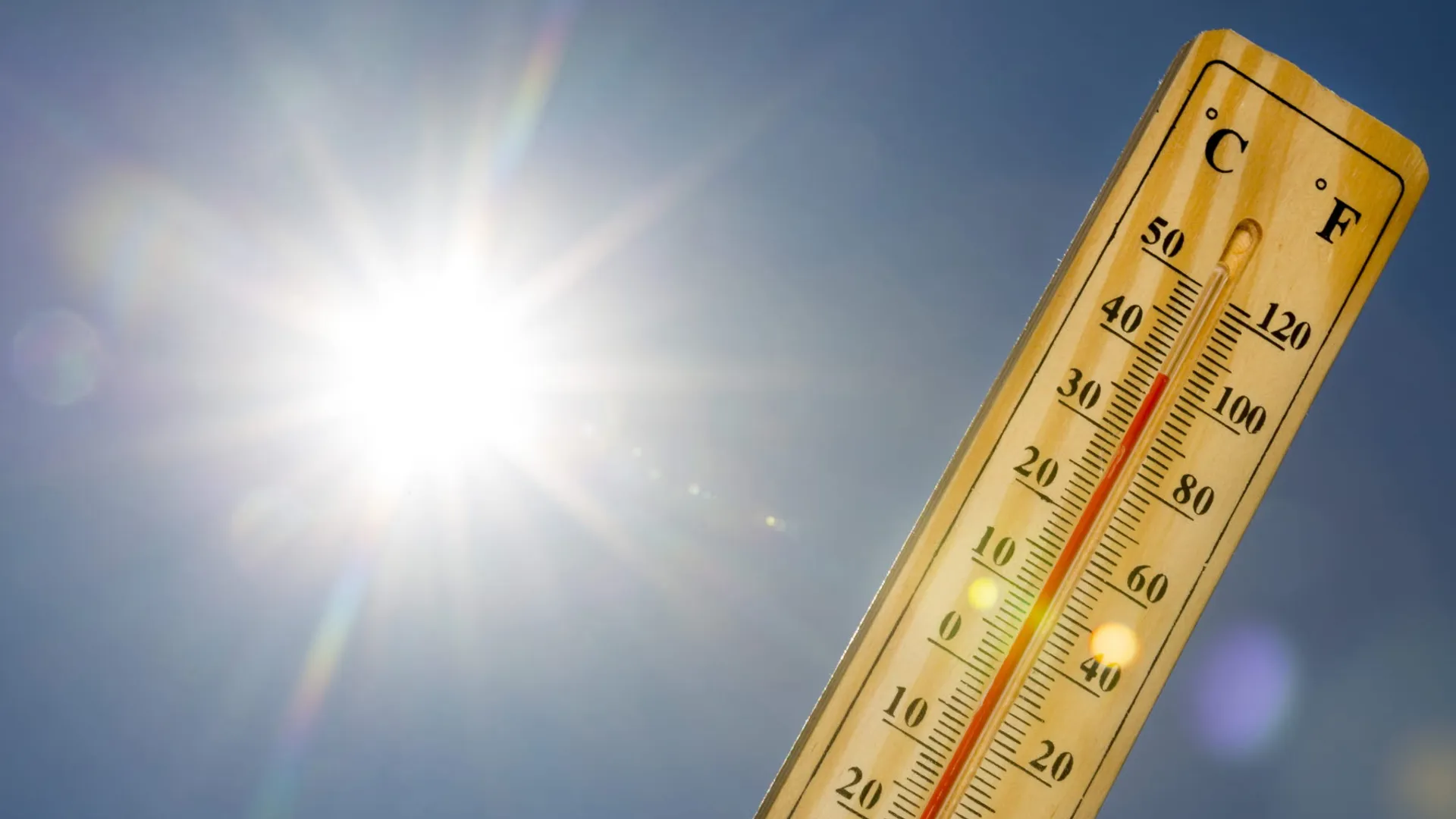 En termometer visar 38 grader, i bakgrunden syns blå himmel och solen.