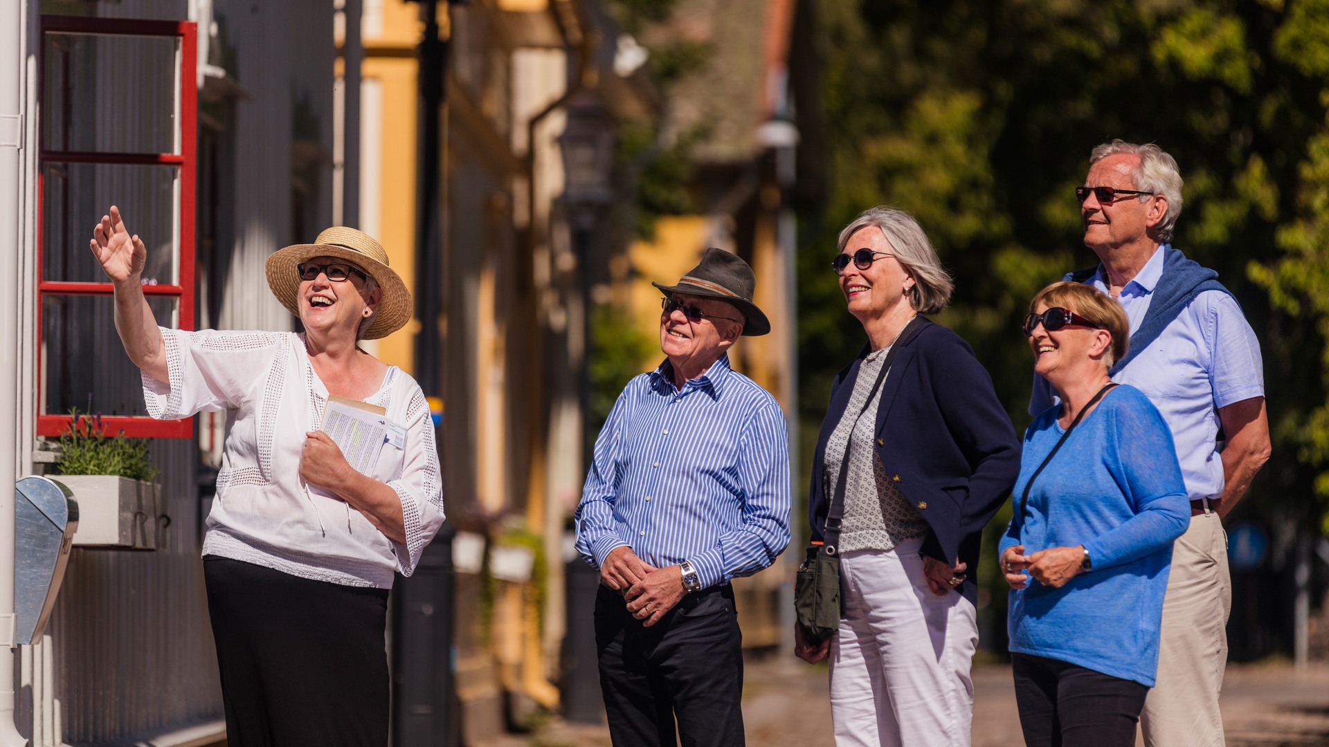En guide visar fyra turister en av villorna i stadsparken.