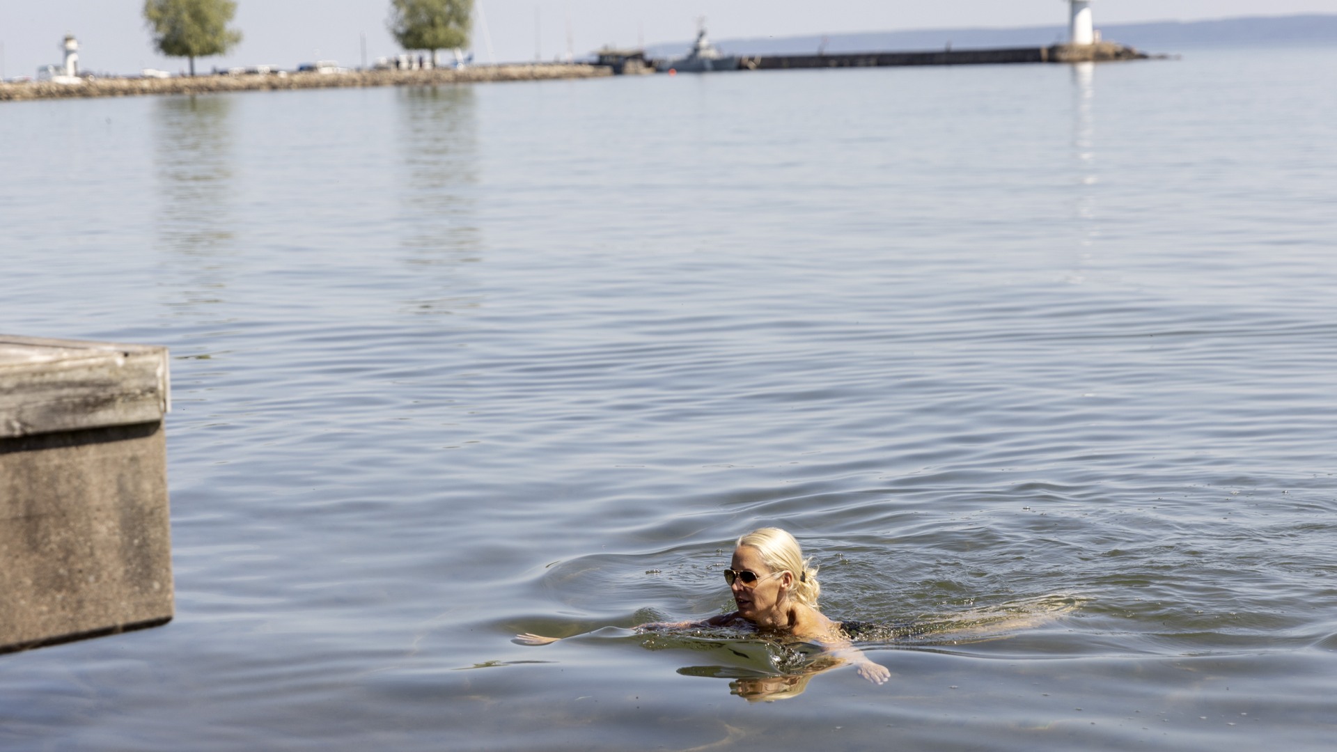 En person simmar i Vättern. Hamnen syns i horisonten.