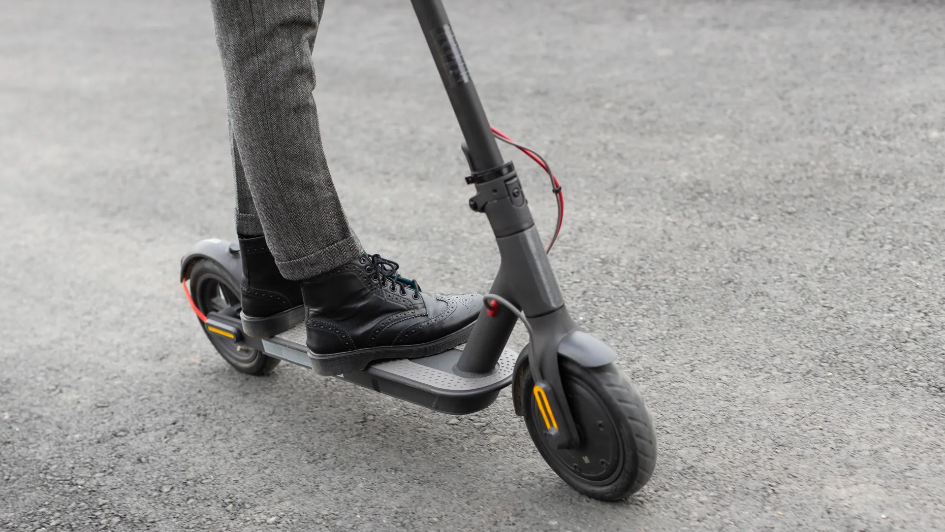 Närbild på en person som åker elsparkcykel. Fötterna och elsparkcykeln syns i bild.
