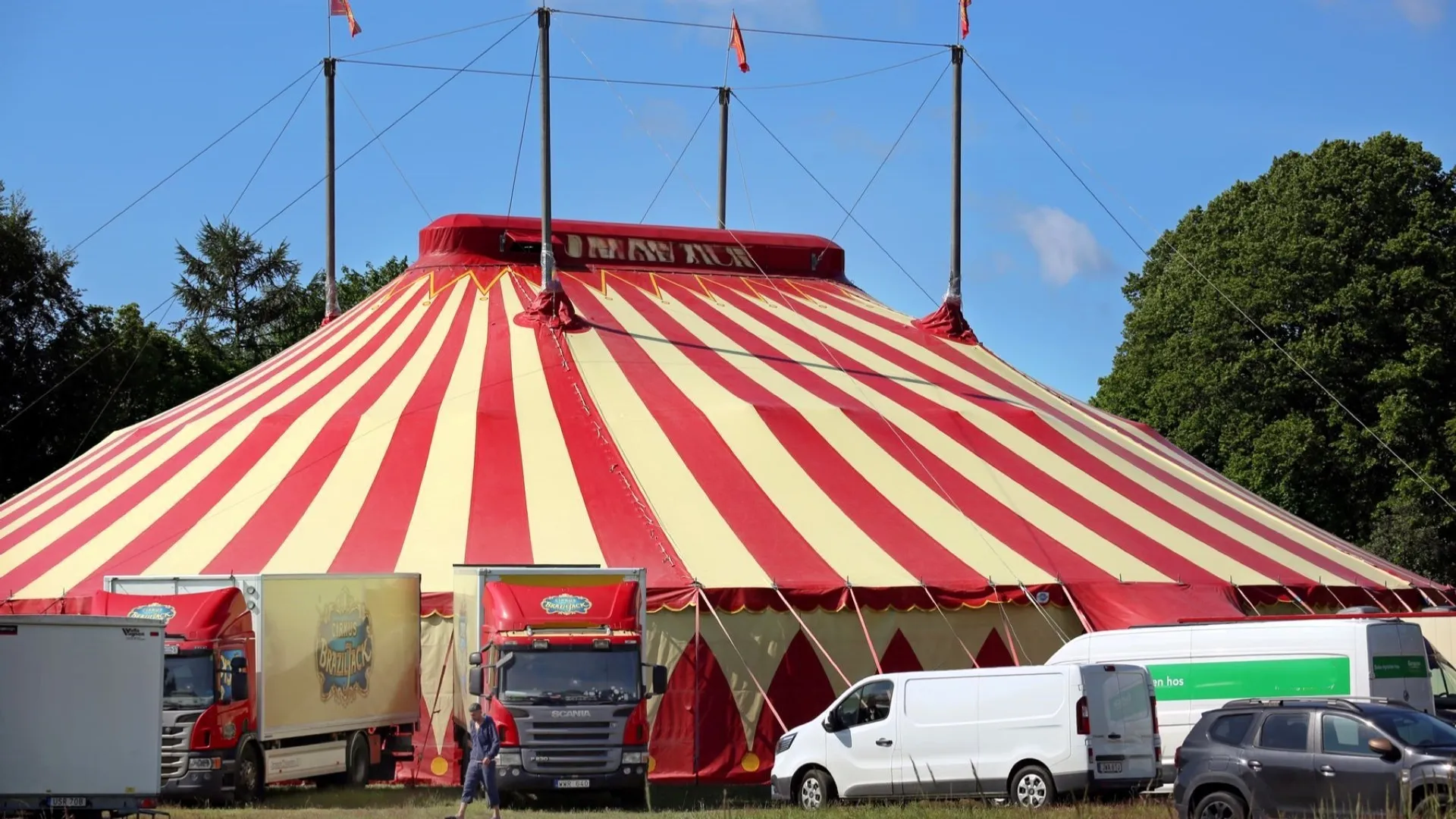 Ett stort cirkustält med flera lastbilar parkerade framför.