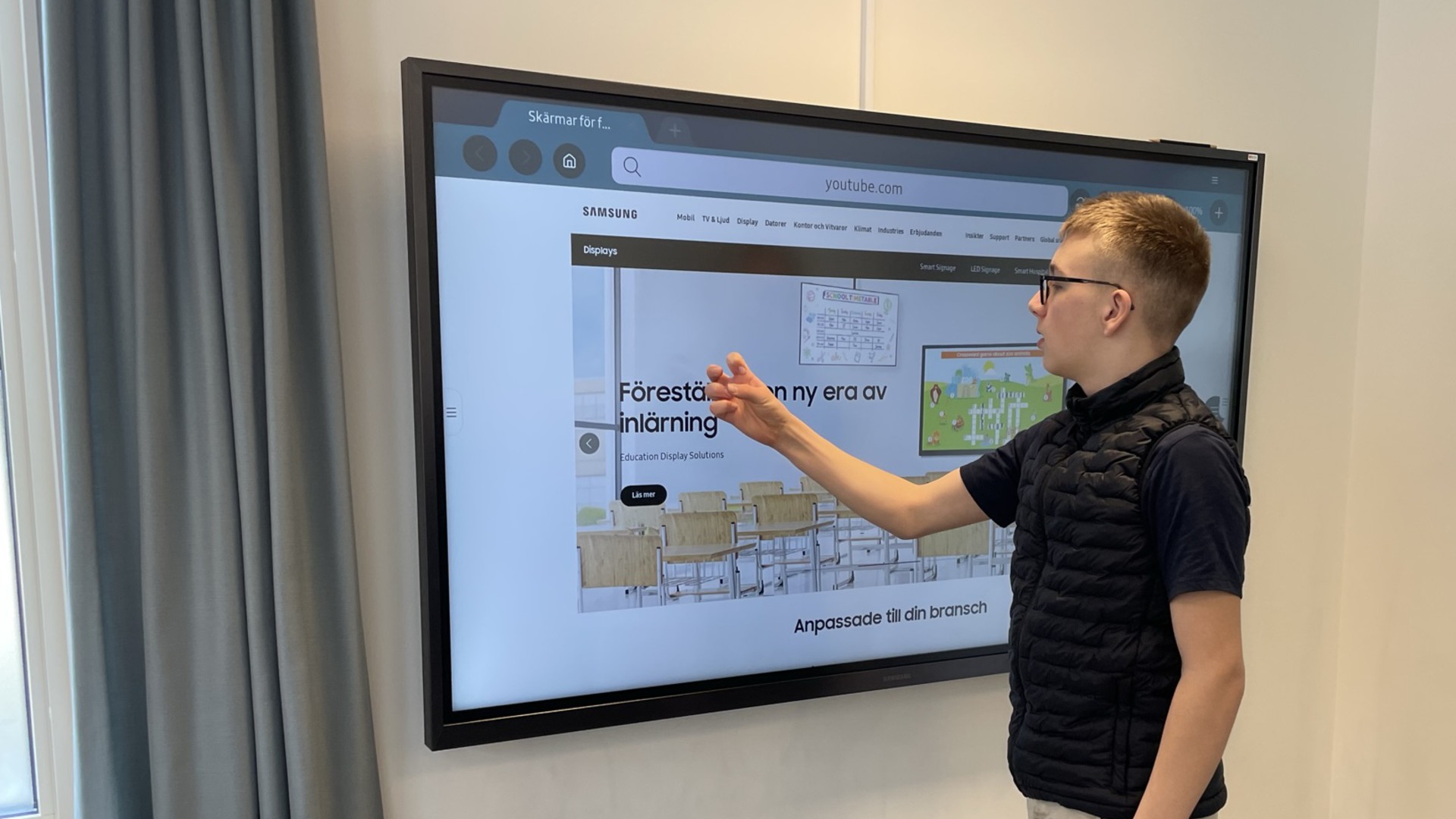 En elev använder en smart skärm som sitter på en vägg.