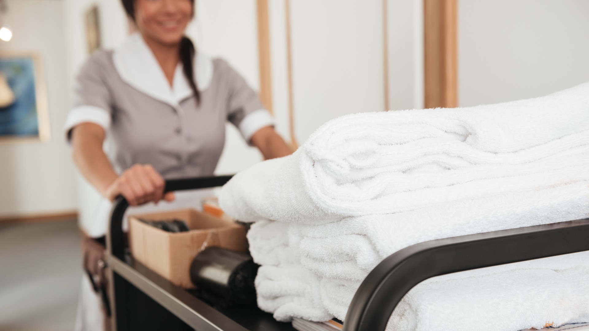 Cropped image of a young hotel maid bringing clean towels and other supplies. Beskuren bild på en ung hotellstäderska som kommer med rena handdukar och andra tillbehör.