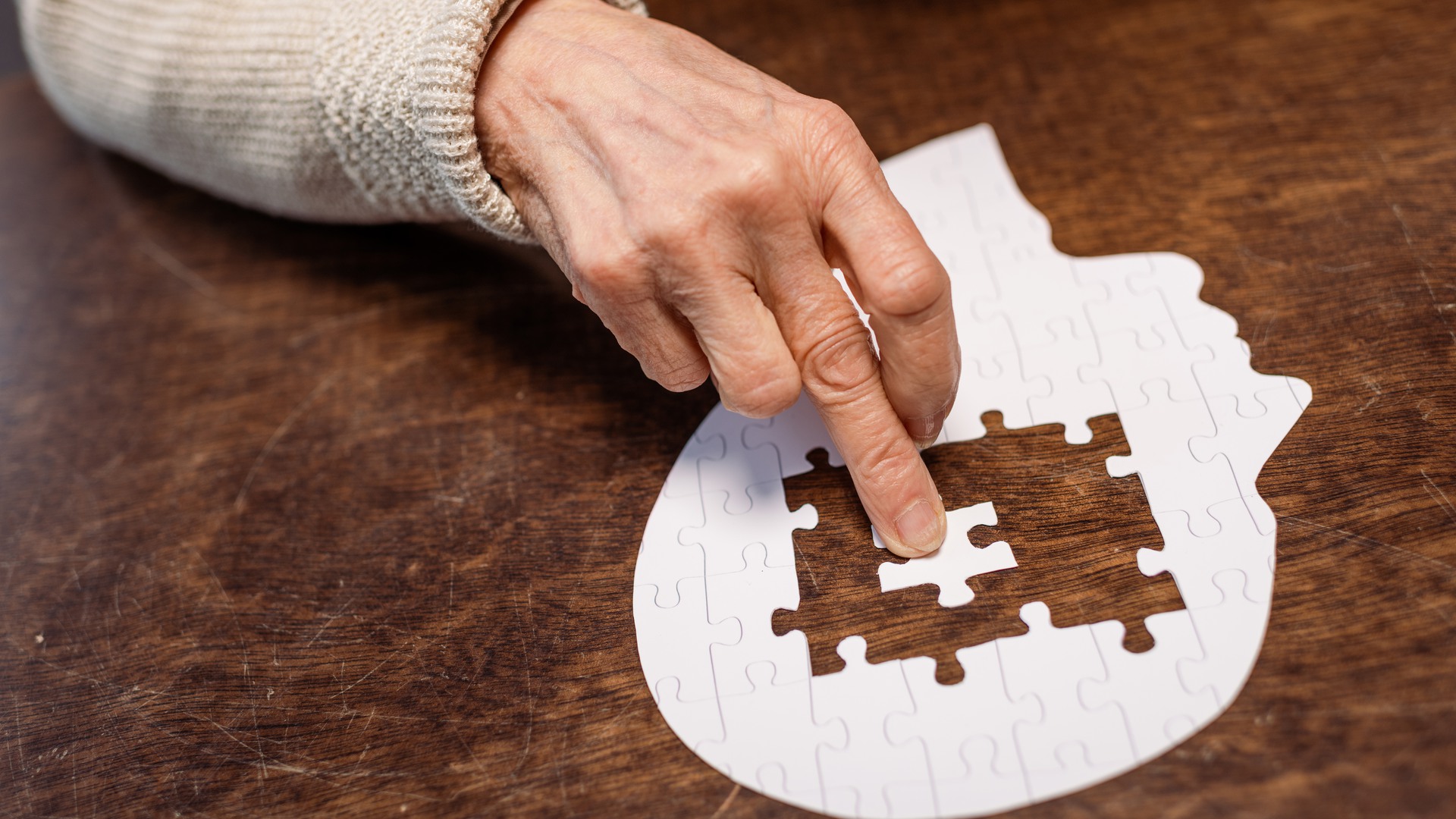 partial view of woman combing jigsaw puzzle as dementia therapy