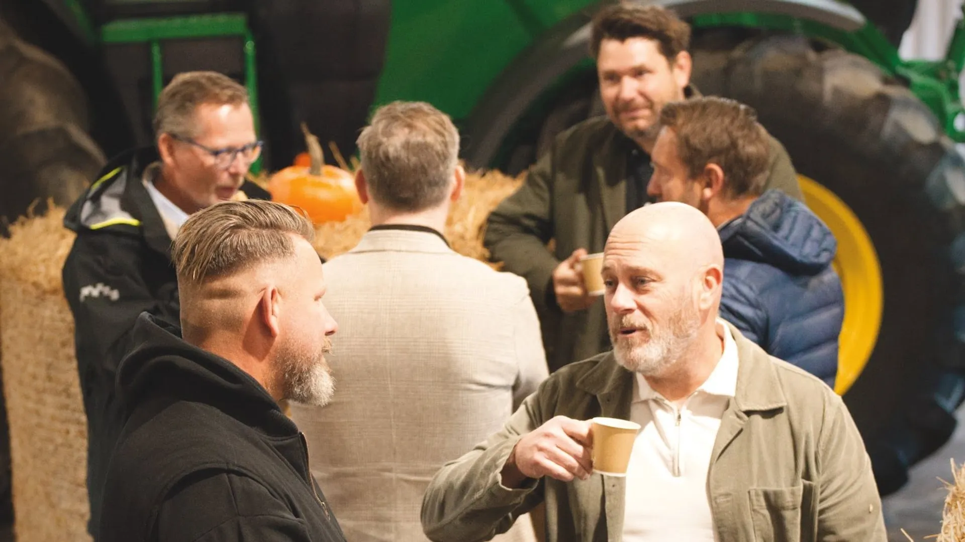 En grupp män som står bredvid varandra framför en traktor.
