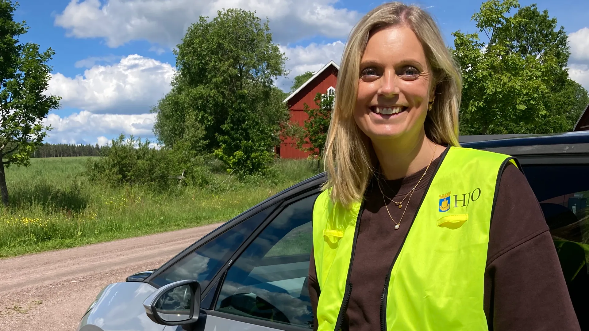Pernilla Borgenhede står framför en bil med Hjo kommuns logga på dörren.