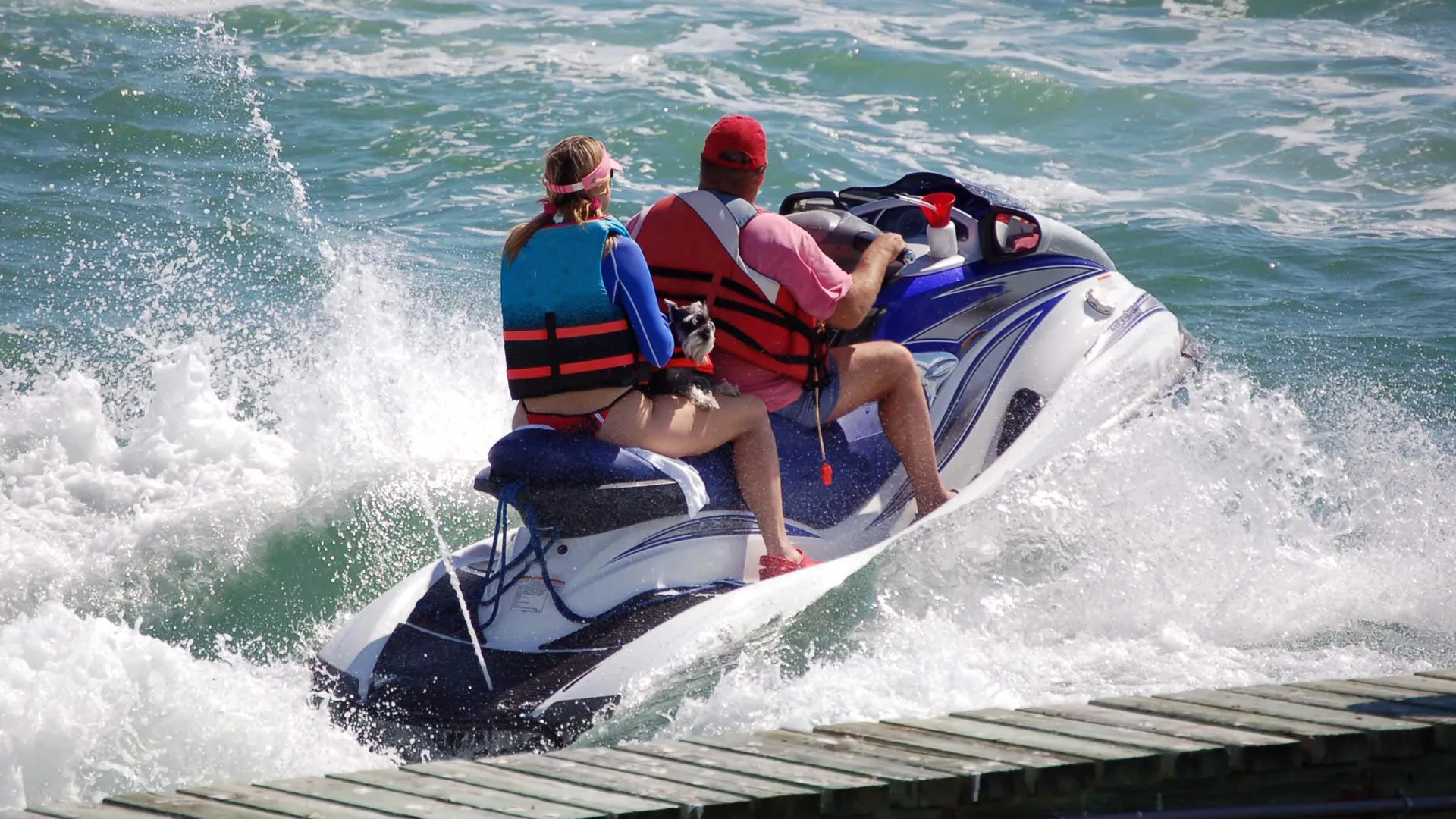 En vattenskoter med två personer vid en brygga.