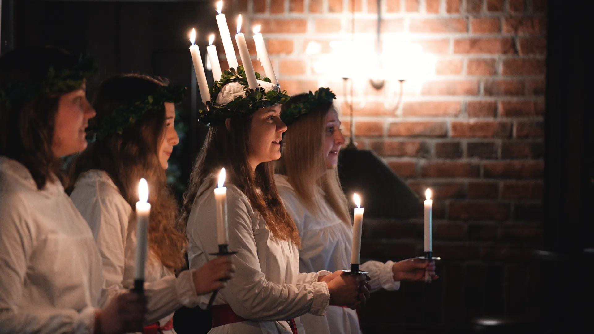 En grupp unga kvinnor som står bredvid varandra och håller i ljus.