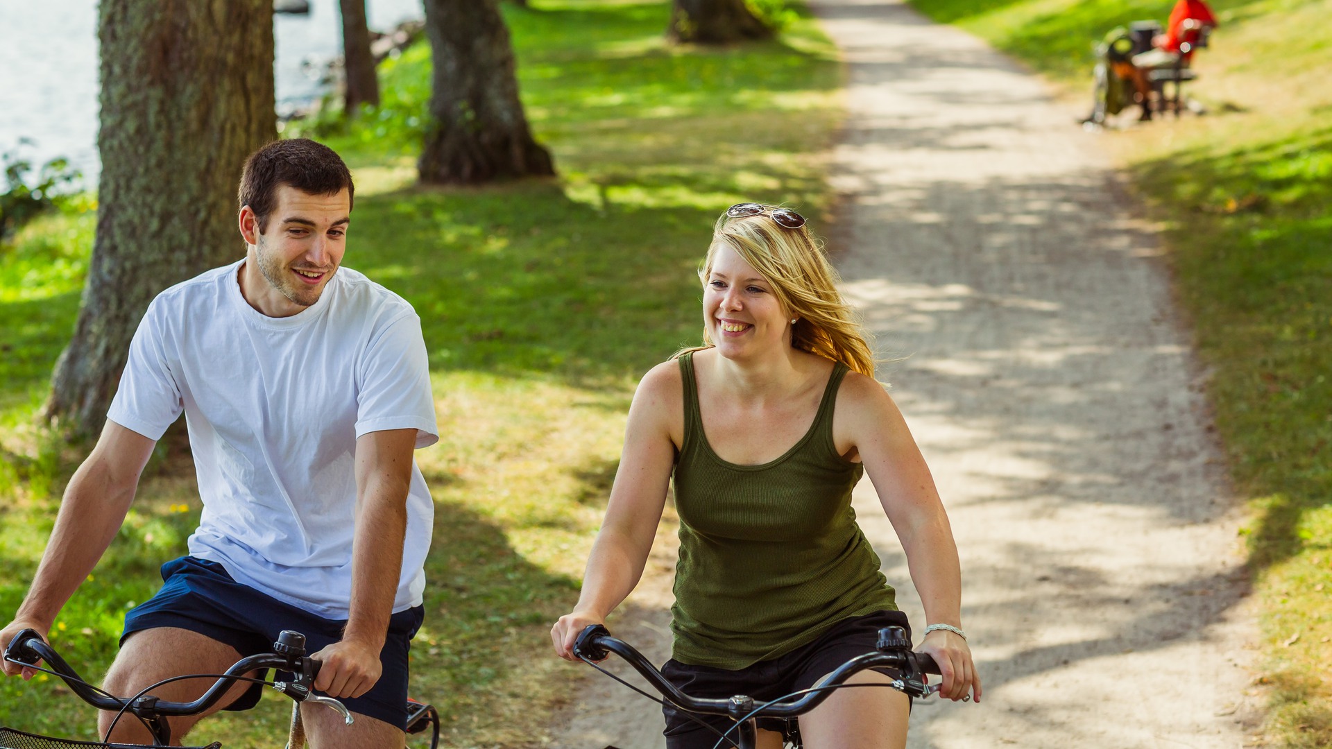 Två unga vuxna cyklar på strandpromenaden.