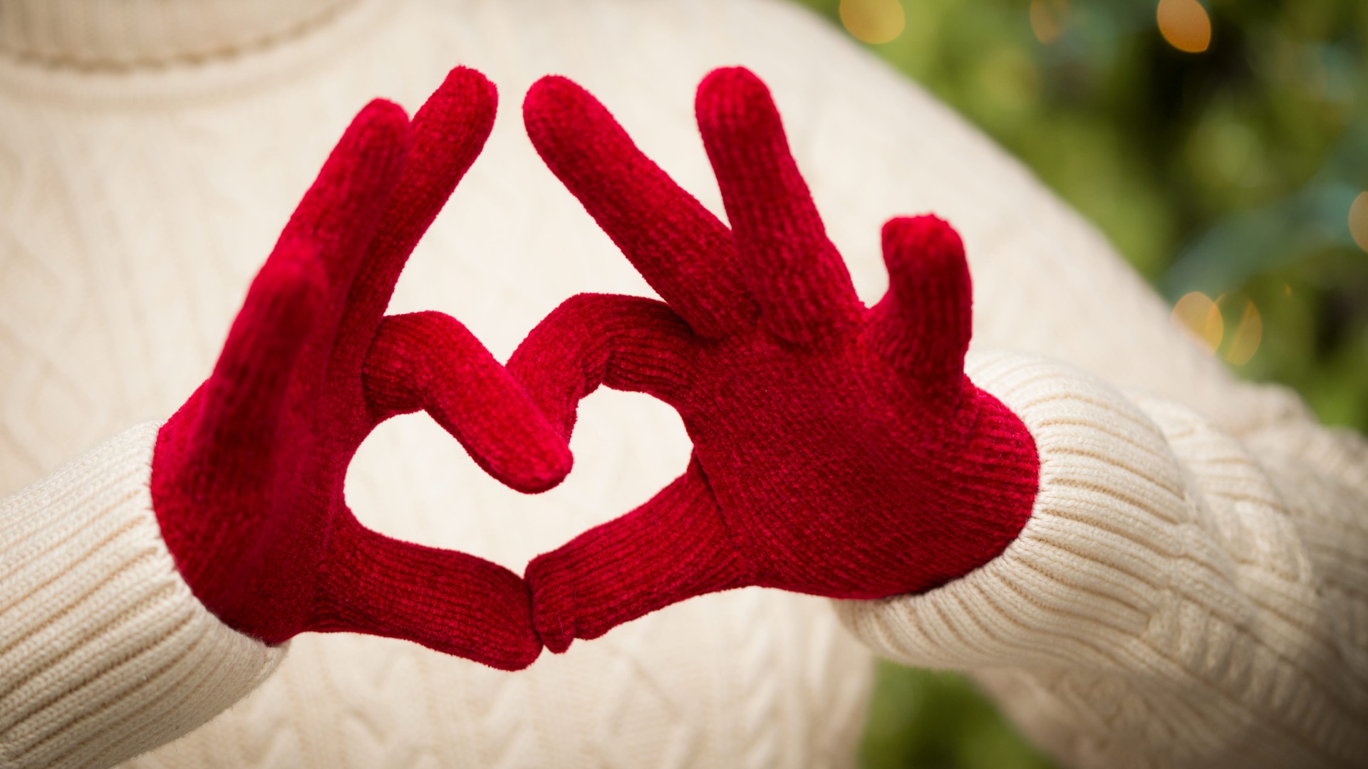 Händer med röda vantar formar ett hjärta.
