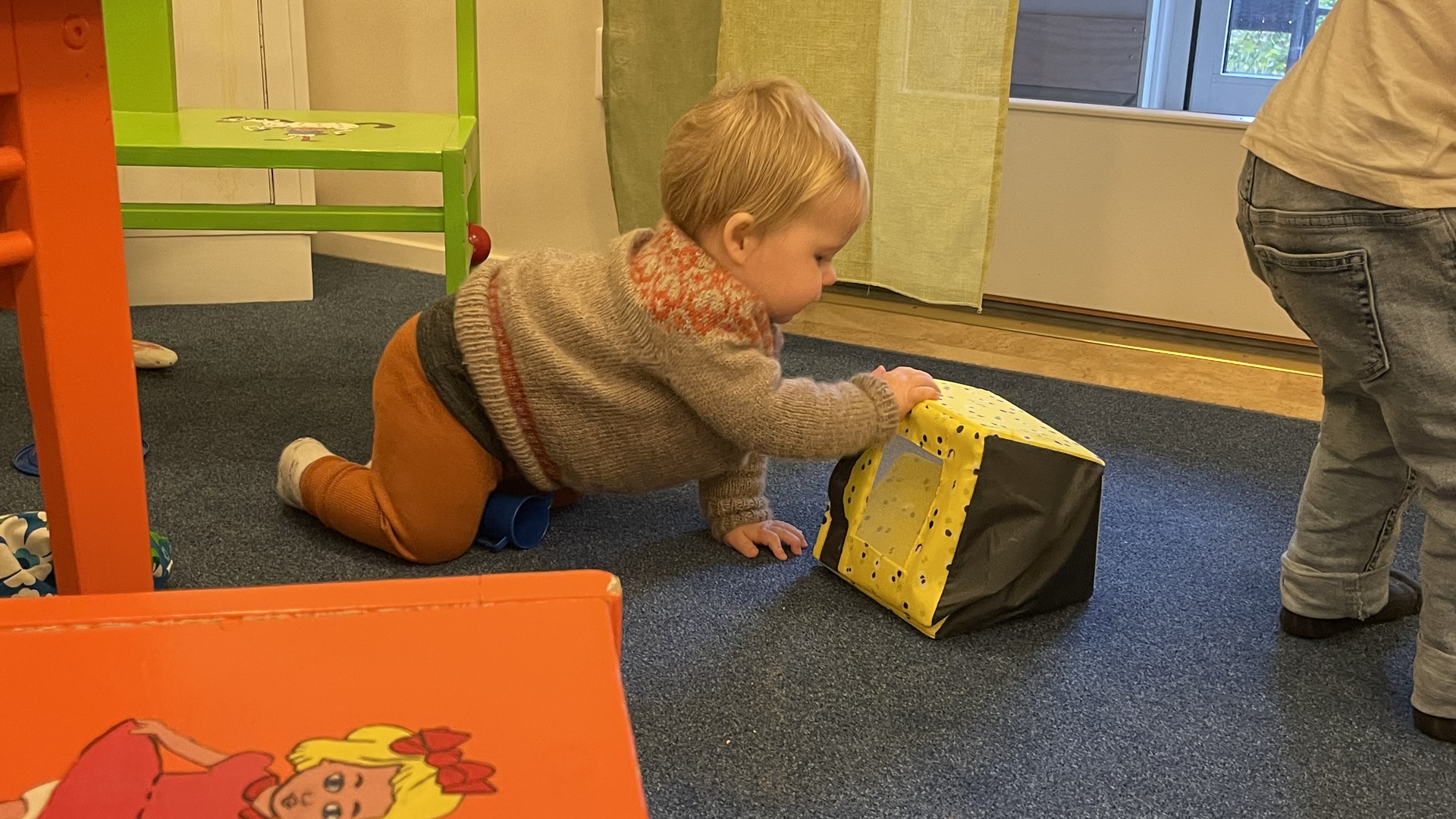 En pojke leker med en förvaringskorg på golvet.
