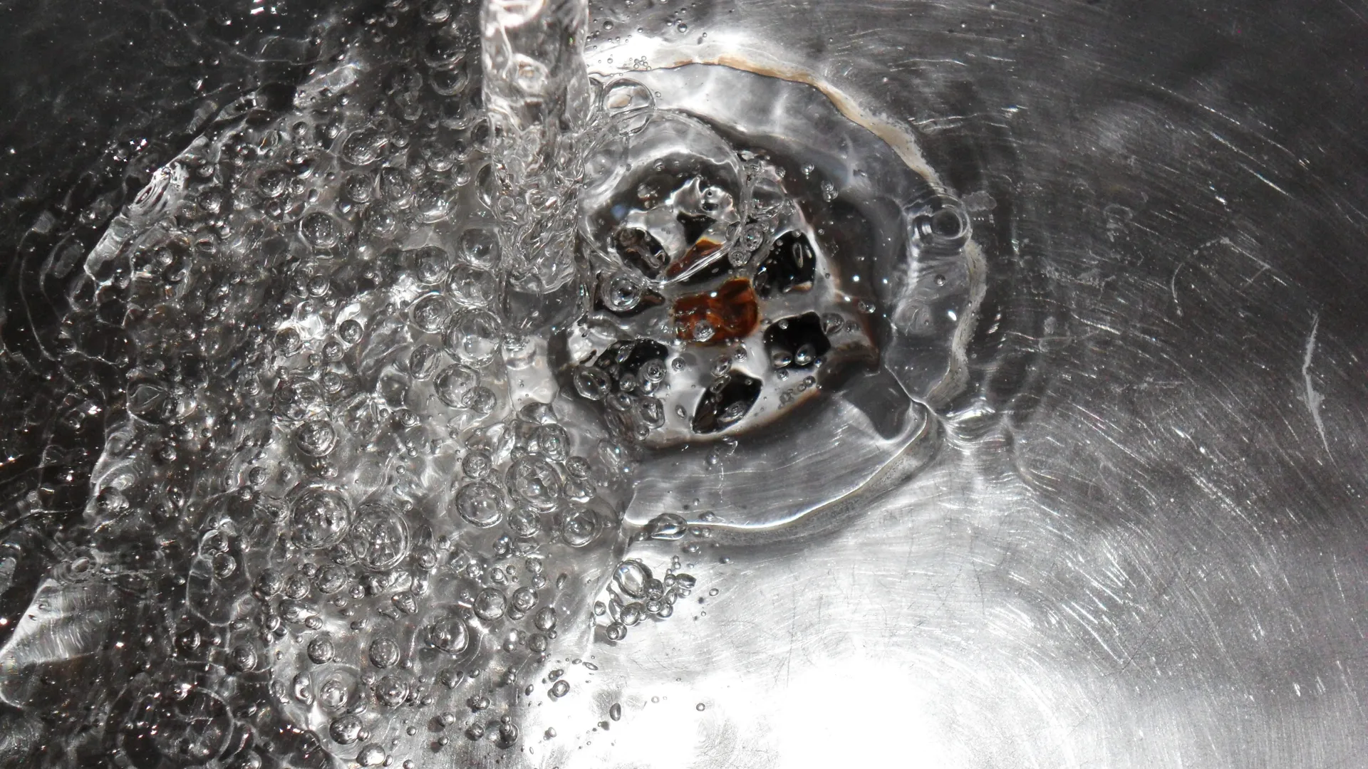 Närbild på vatten som rinner ner i ett handfat. 