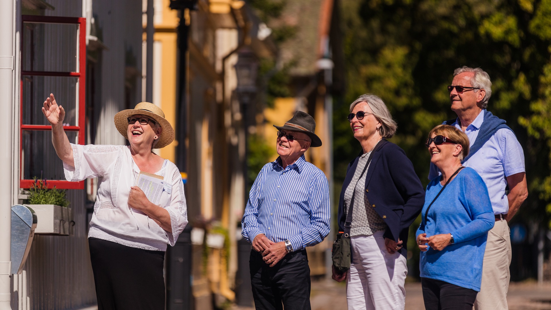 En guide visar fyra turister en av villorna i stadsparken.