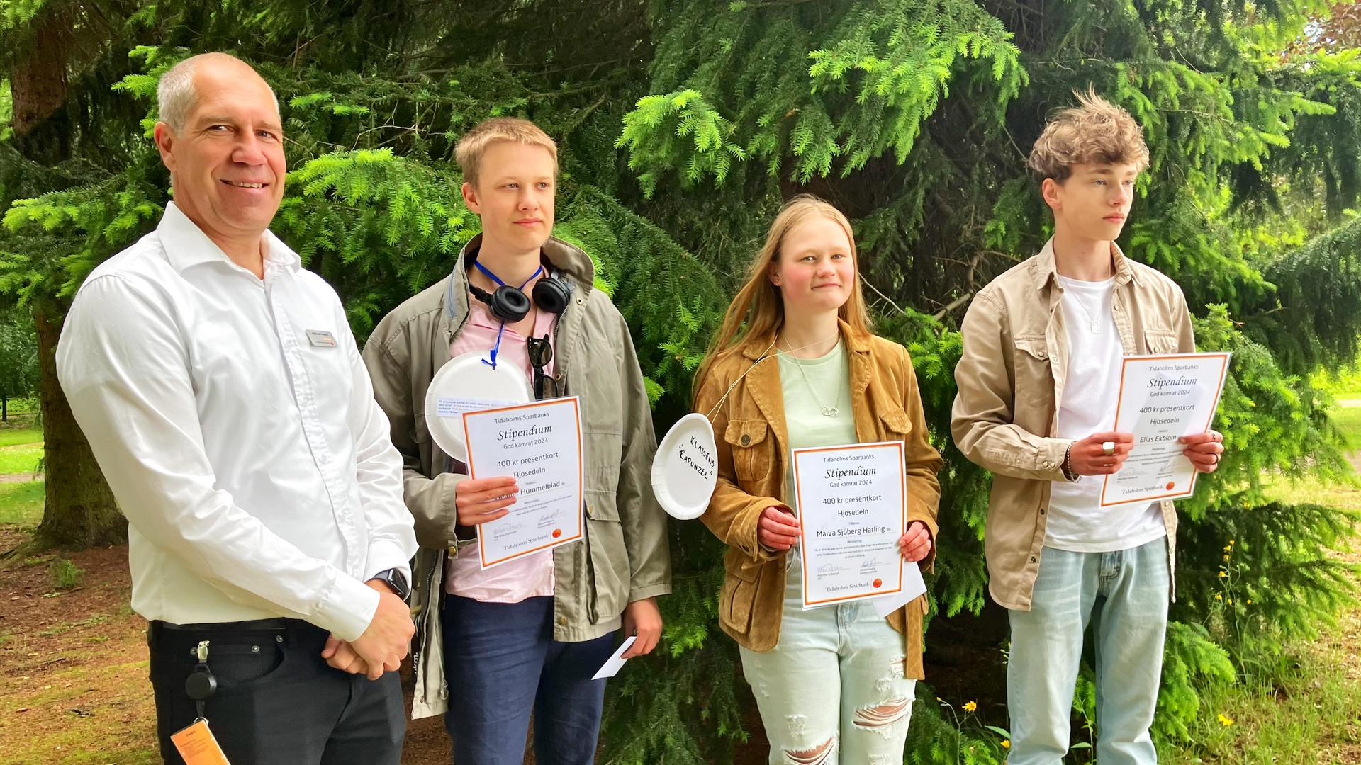 Tre elever står med sina diplom, tillsammans med en från Tidaholms sparbank.