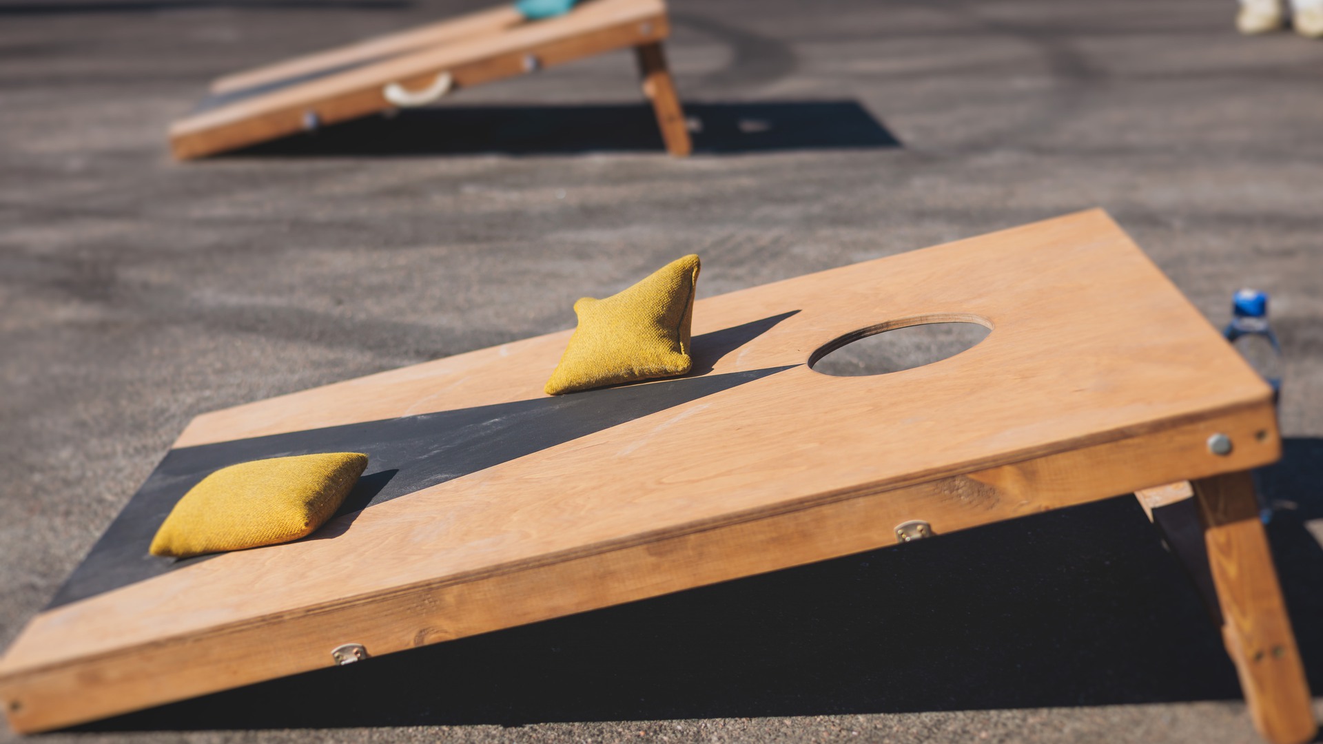 Cornhole game set, process of throwing bean bags, kids children tossing bean sacks, corn hole  in the backyard, wooden boards for corn-hole tournament in the summer sunny day