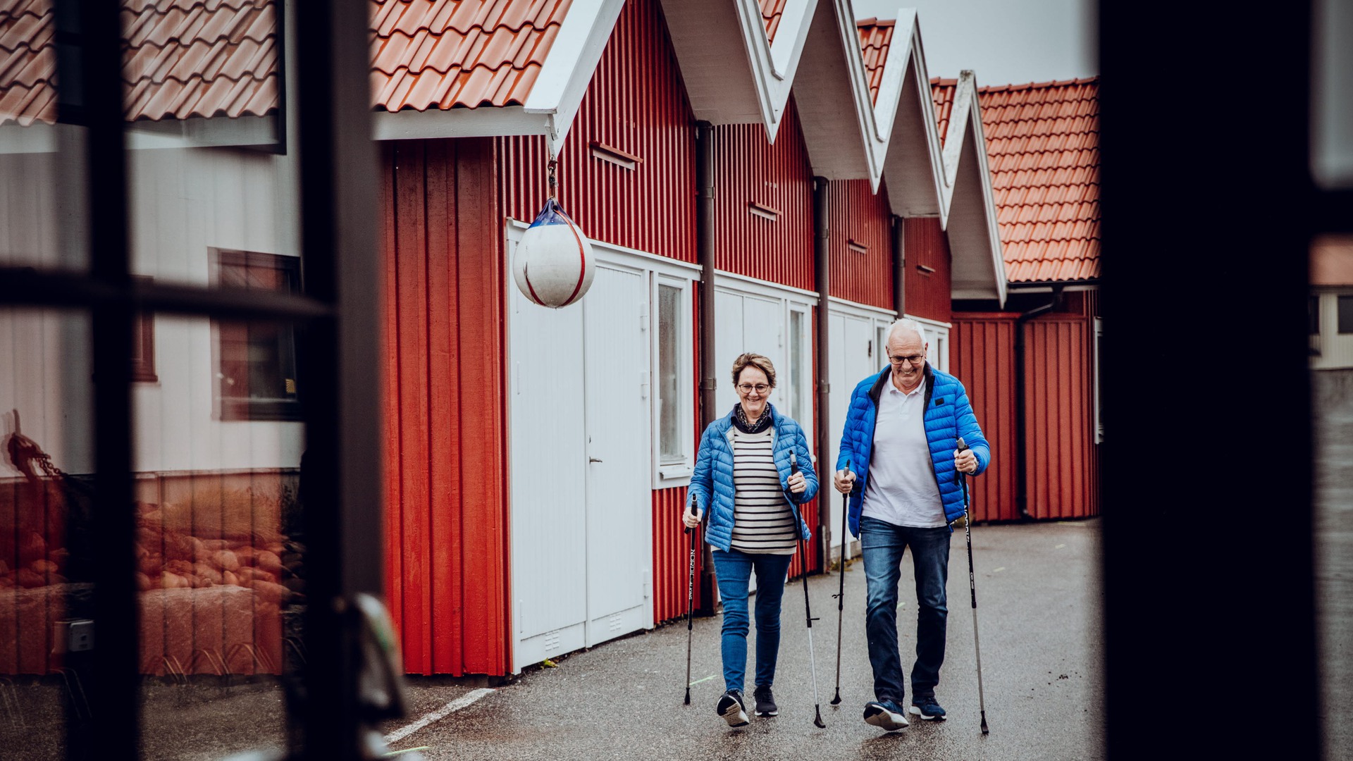 Ett äldre par promenerar med stavar i Hjo hamn.