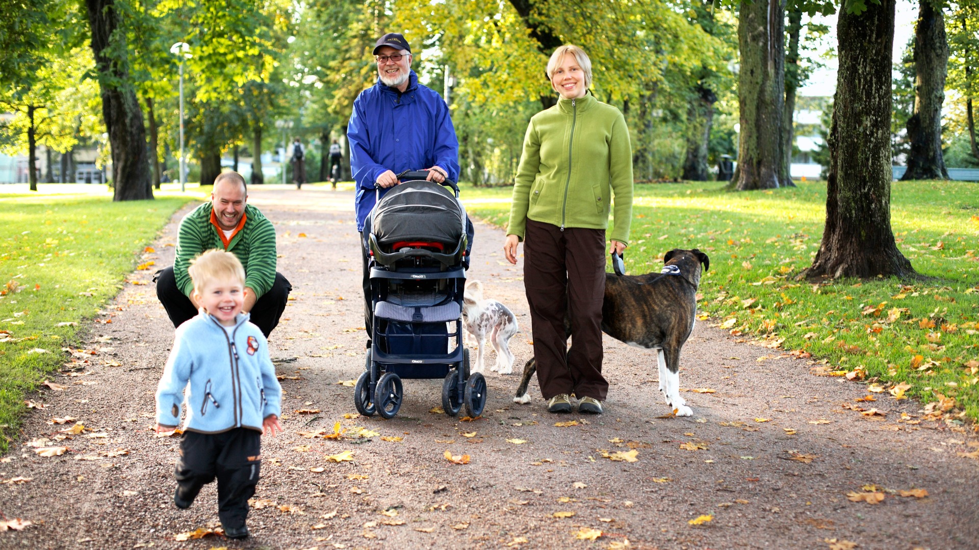 En familj med hund på promenad i en park.